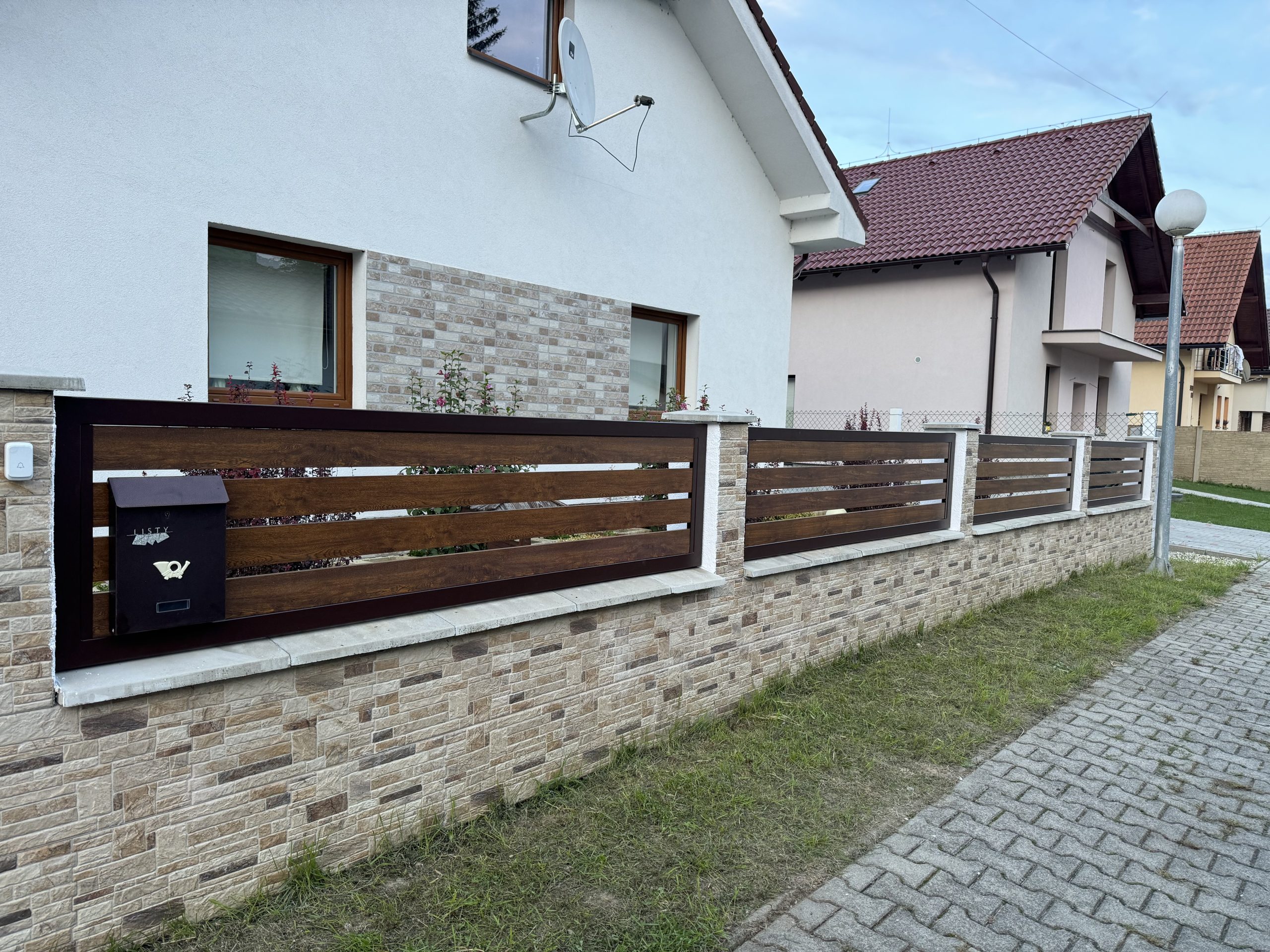 Precízna kovovýroba na mieru MFZVAR, moderný kovový plot okolo celého pozemku v kombinácii s drevom.